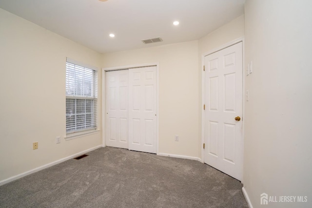 unfurnished bedroom featuring dark carpet and a closet