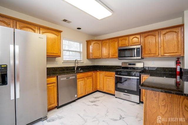 kitchen with stainless steel appliances, sink, and dark stone countertops