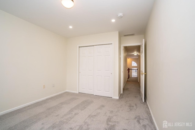 unfurnished bedroom featuring light carpet and a closet