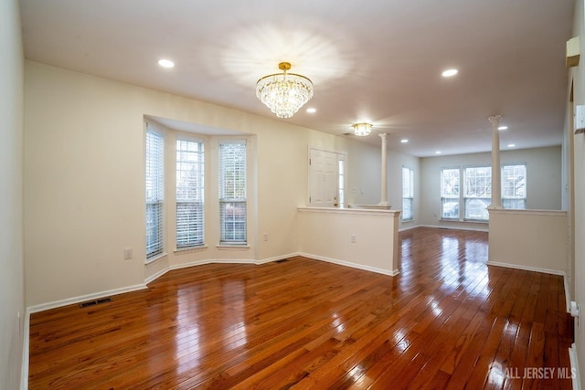 unfurnished living room with an inviting chandelier and hardwood / wood-style floors