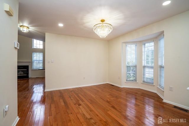 empty room with hardwood / wood-style floors and a notable chandelier