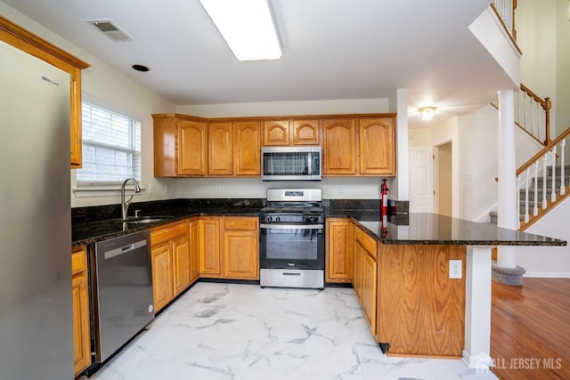 kitchen featuring appliances with stainless steel finishes, sink, kitchen peninsula, and dark stone counters