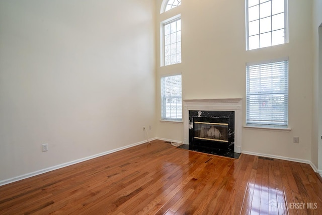 unfurnished living room featuring a high ceiling, hardwood / wood-style floors, and a fireplace