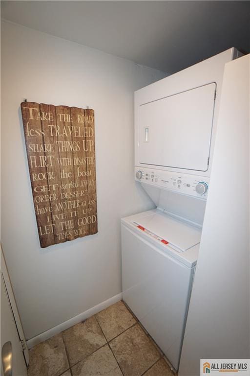 washroom featuring stacked washing machine and dryer, tile patterned floors, and baseboards