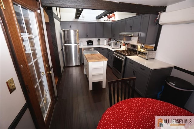 kitchen featuring stainless steel appliances, a sink, dark wood-type flooring, wood counters, and tasteful backsplash