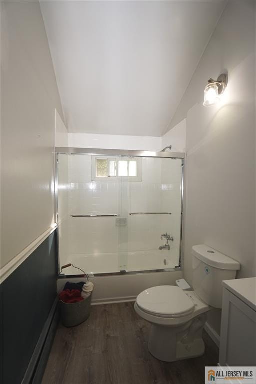 bathroom with vaulted ceiling, wood finished floors, toilet, combined bath / shower with glass door, and vanity