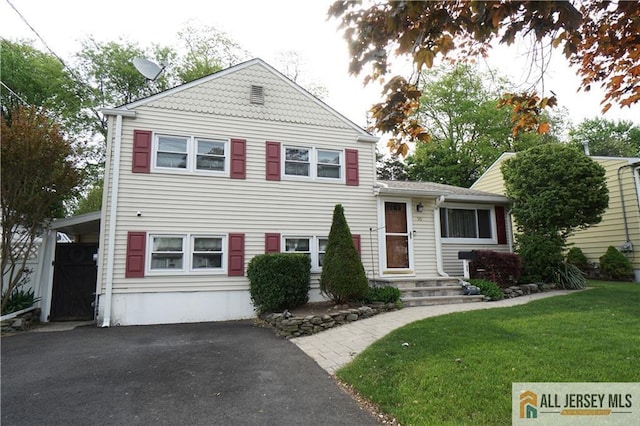 split level home with asphalt driveway and a front lawn