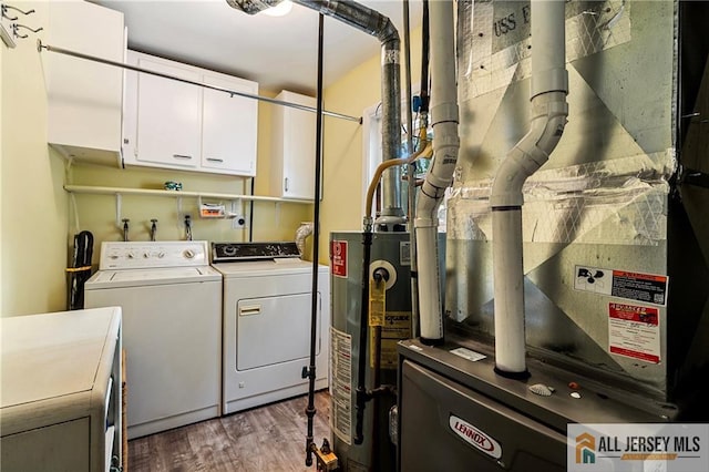 clothes washing area with light hardwood / wood-style flooring, heating unit, cabinets, gas water heater, and washing machine and dryer