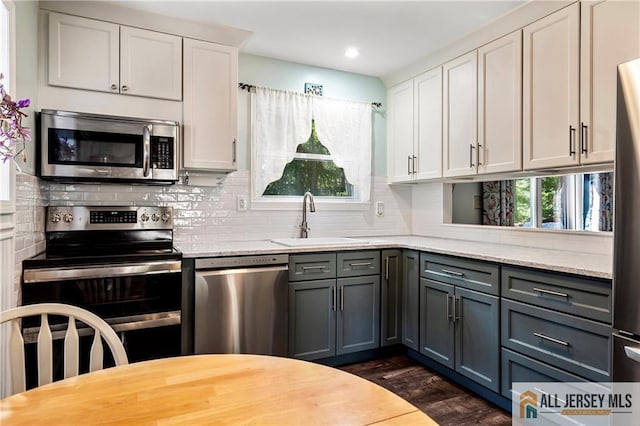 kitchen featuring appliances with stainless steel finishes, white cabinets, a healthy amount of sunlight, and sink