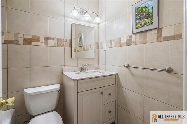 bathroom with vanity, toilet, and tile walls