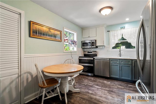 kitchen with decorative backsplash, white cabinets, dark wood-type flooring, sink, and stainless steel appliances