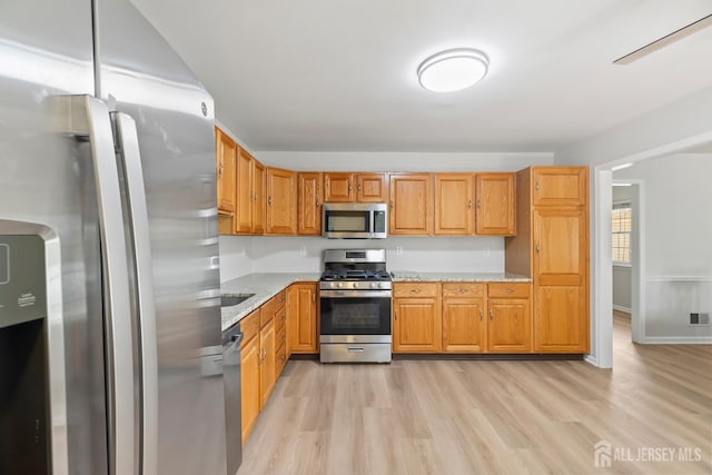334 Waterside Blvd, Monroe, NJ 08831 - kitchen featuring stainless steel appliances, light wood-type flooring, light stone counters, and brown cabinets