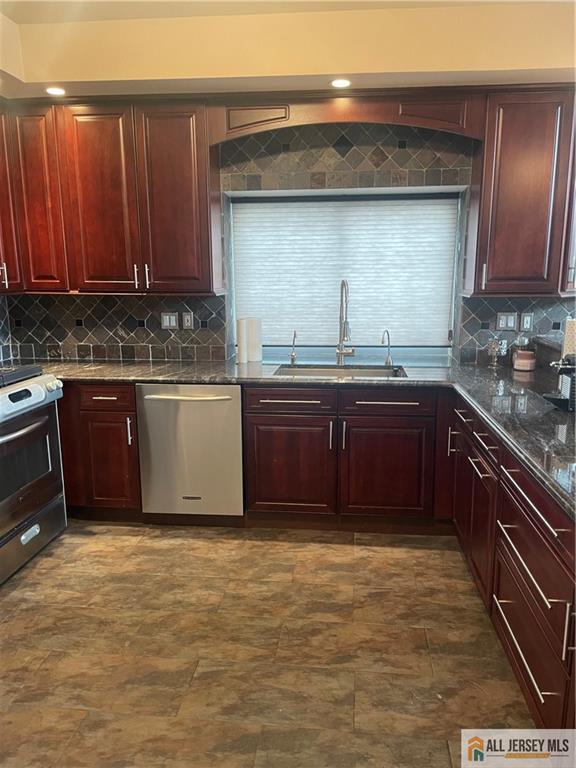 kitchen featuring a sink, dark brown cabinets, appliances with stainless steel finishes, backsplash, and dark stone counters