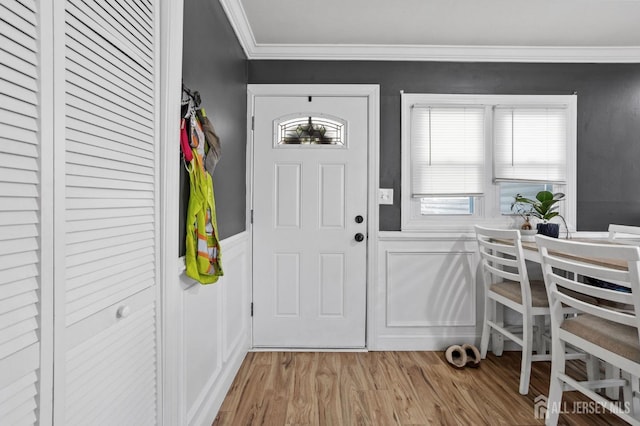 foyer entrance with wainscoting, light wood-type flooring, and crown molding