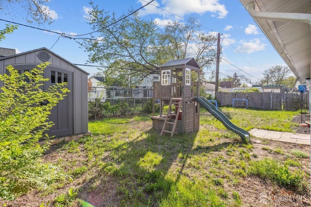 view of play area featuring an outdoor structure, a shed, a yard, and a fenced backyard
