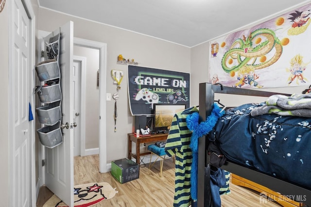 bedroom featuring ornamental molding, a closet, wood finished floors, and baseboards