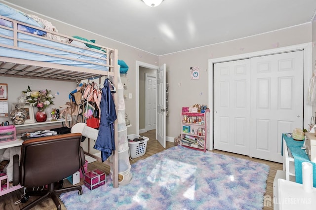 bedroom with wood finished floors and a closet