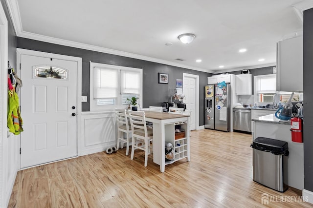 kitchen with light wood-type flooring, stainless steel appliances, a wealth of natural light, and crown molding