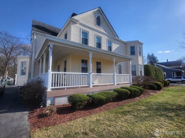 farmhouse inspired home featuring a porch and a front lawn