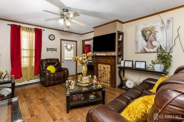 living area with a ceiling fan, ornamental molding, and wood finished floors