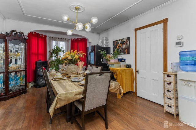 dining space with crown molding, an inviting chandelier, a baseboard radiator, and wood finished floors
