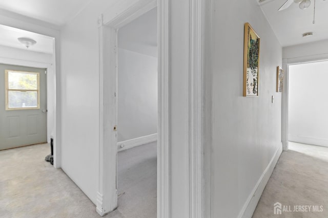 corridor with baseboards and light colored carpet