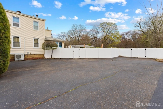 exterior space with a gate, fence, ac unit, and driveway