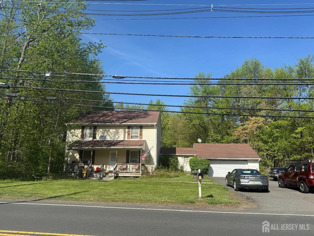 colonial inspired home with a garage, covered porch, and a front lawn