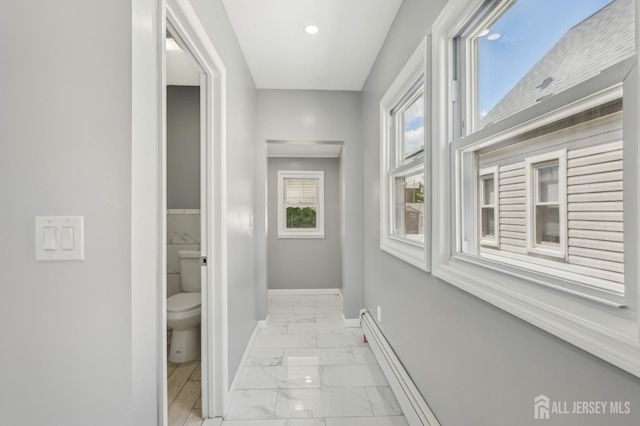 hallway featuring light marble finish flooring, baseboards, and baseboard heating