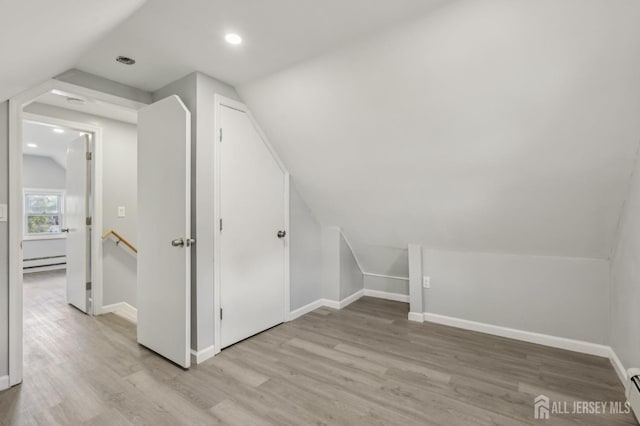 additional living space featuring a baseboard heating unit, lofted ceiling, light wood finished floors, baseboards, and recessed lighting