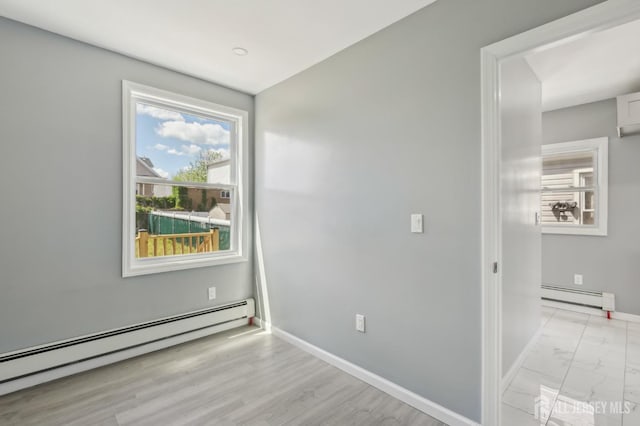 unfurnished room with a baseboard radiator, baseboards, and light marble finish floors