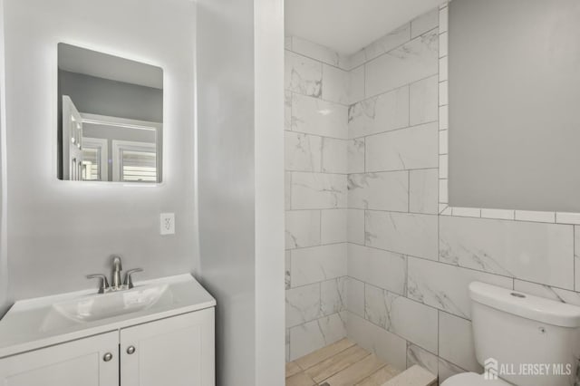bathroom with a stall shower, toilet, and vanity