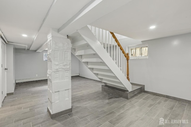 basement featuring baseboards, recessed lighting, stairs, light wood-style flooring, and a baseboard radiator