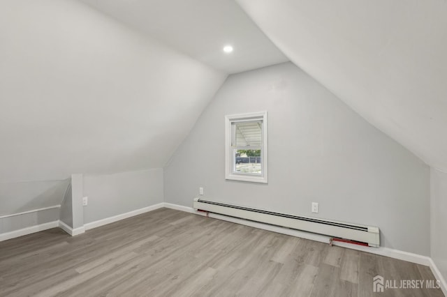 additional living space featuring a baseboard heating unit, wood finished floors, lofted ceiling, baseboards, and recessed lighting