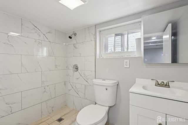 bathroom featuring vanity, toilet, and a tile shower