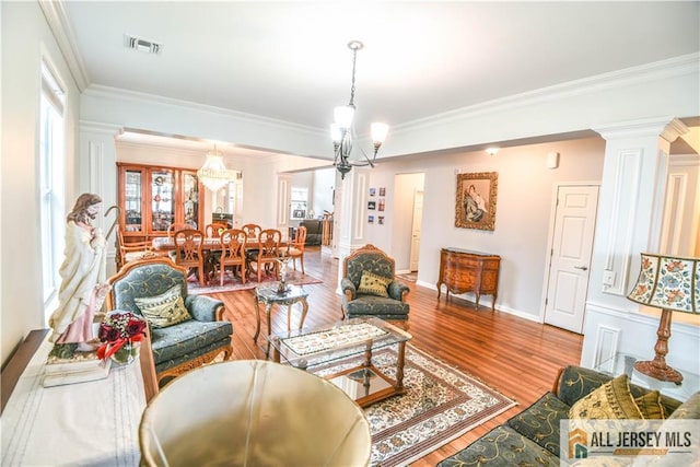 living area with wood finished floors, visible vents, ornamental molding, baseboards, and decorative columns