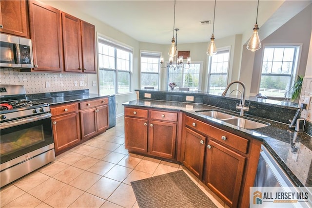 kitchen featuring stainless steel appliances, a sink, an inviting chandelier, decorative light fixtures, and light tile patterned floors