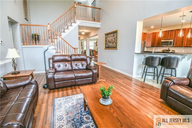 living room with stairway, wood finished floors, a high ceiling, and baseboards