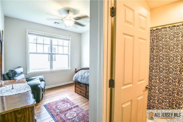 bedroom with baseboards, wood finished floors, visible vents, and a ceiling fan