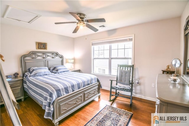 bedroom featuring a ceiling fan, wood finished floors, attic access, baseboards, and visible vents