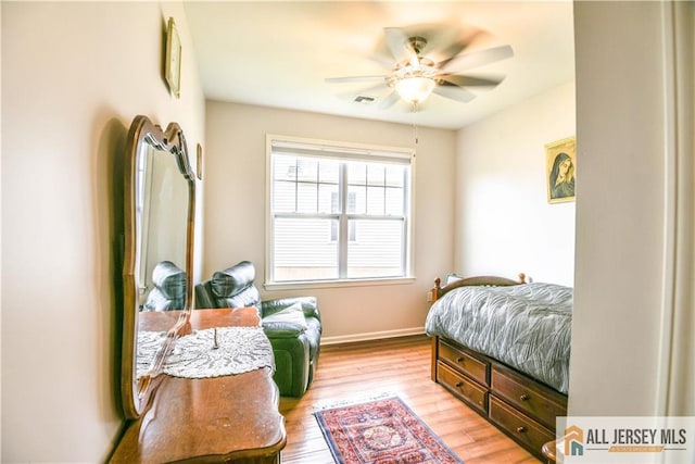 bedroom featuring baseboards, a ceiling fan, visible vents, and light wood-style floors