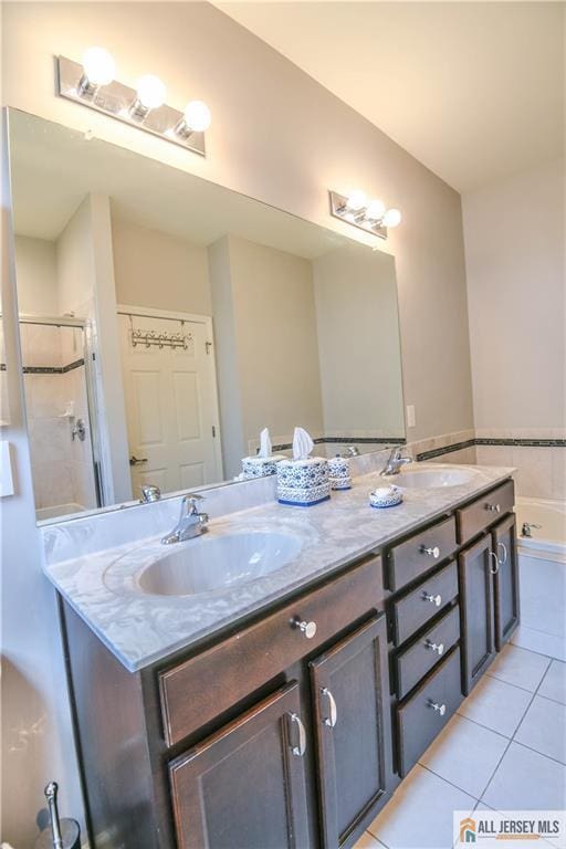 bathroom with tile patterned floors, a sink, double vanity, and a stall shower