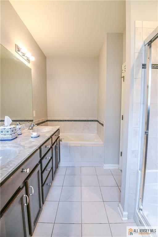 bathroom featuring tile patterned floors, a garden tub, a sink, and a stall shower