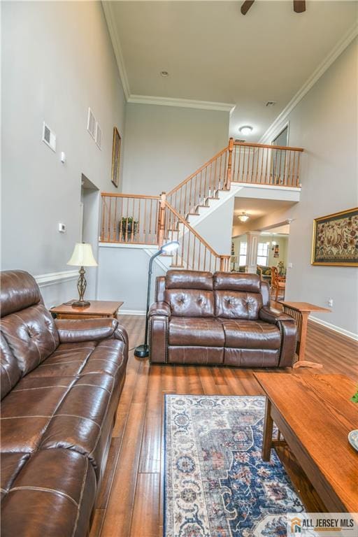 living area featuring visible vents, ornamental molding, stairs, and wood-type flooring