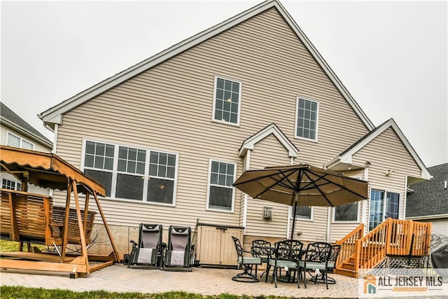 back of house with a wooden deck and a patio