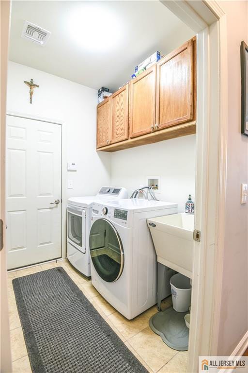 clothes washing area featuring visible vents, washer and dryer, light tile patterned floors, and cabinet space