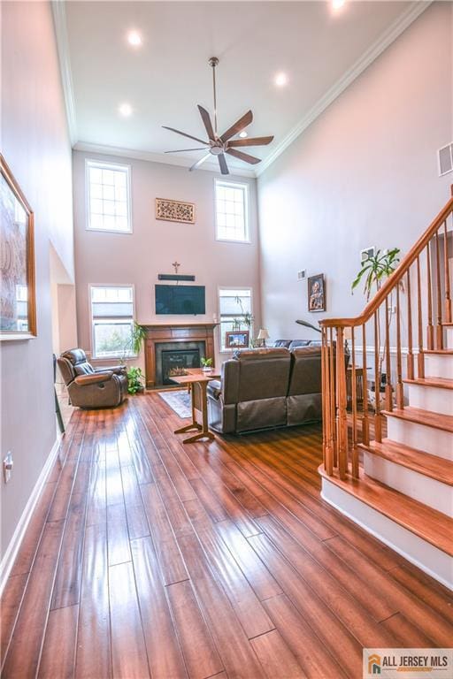 living area with hardwood / wood-style floors, a ceiling fan, stairway, and ornamental molding