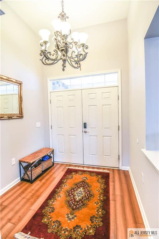 entrance foyer with plenty of natural light, wood finished floors, and an inviting chandelier