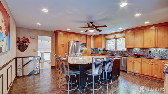 15 Timber Rd, East Brunswick, NJ 08816 - kitchen featuring appliances with stainless steel finishes, a kitchen island, a ceiling fan, light stone counters, and decorative backsplash