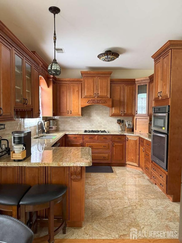117 Providence Blvd, South Brunswick, NJ 08824 - kitchen featuring appliances with stainless steel finishes, a peninsula, brown cabinets, and hanging light fixtures